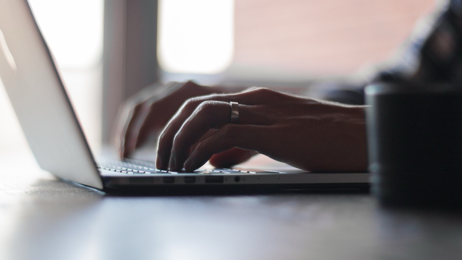 Hands typing on a MacBook keyboard during macOS desktop setup